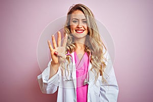 Young beautiful doctor woman using stethoscope over pink isolated background showing and pointing up with fingers number four