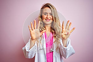 Young beautiful doctor woman using stethoscope over pink isolated background showing and pointing up with fingers number nine