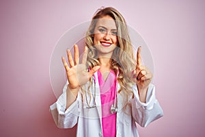 Young beautiful doctor woman using stethoscope over pink isolated background showing and pointing up with fingers number six while
