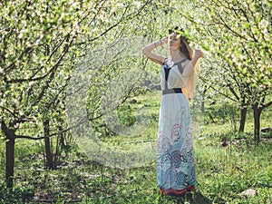 Young beautiful dreaming woman in spring blossom trees.
