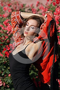 Young beautiful dreamy woman with closed eyes posing in garden of roses. Outdoor fashion portrait of romantic girl with hard