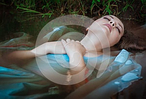 Young beautiful drowned woman lying in the water