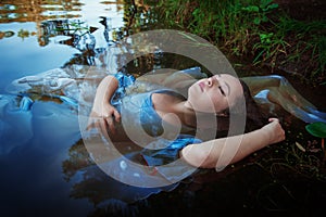 Young beautiful drowned woman lying in the water