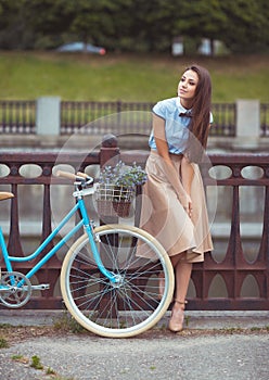 Young beautiful, elegantly dressed woman with bicycle outdoor