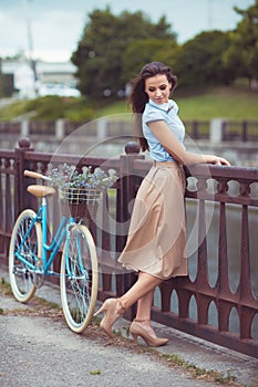 Young beautiful, elegantly dressed woman with bicycle outdoor