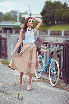 Young beautiful, elegantly dressed woman with bicycle outdoor