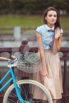 Young beautiful, elegantly dressed woman with bicycle in the par