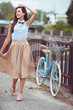 Young beautiful, elegantly dressed woman with bicycle in the par