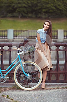 Young beautiful, elegantly dressed woman with bicycle, summer an