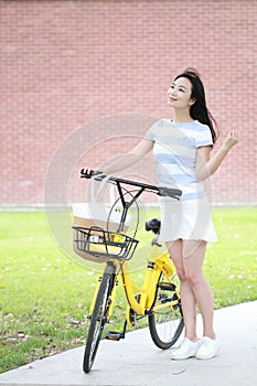 Young beautiful, elegantly dressed woman with Sharing bicycle. Beauty, fashion and lifestyle