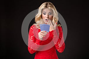 Young beautiful emotional woman with cards in hands on a black background in the studio. Poker