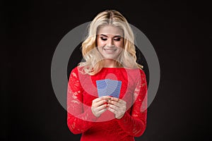 Young beautiful emotional woman with cards in hands on a black background in the studio. Poker