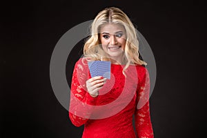 Young beautiful emotional woman with cards in hands on a black background in the studio. Poker