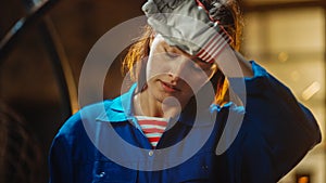 Young Beautiful Empowering Woman Rubs Her Forehead. Authentic Fabricator Wearing Work Clothes in a