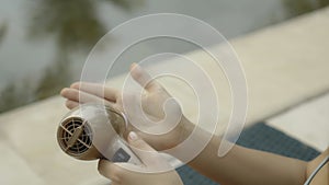 Young and beautiful European girl in a swimsuit using an electric device for arms skin care