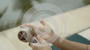 Young and beautiful European girl in a swimsuit using an electric device for arms skin care