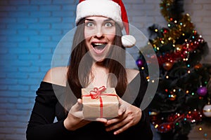 Young beautiful excited woman in evening dress and Santa cap hol