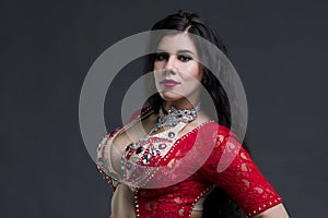 Young beautiful exotic eastern women in ethnic red dress on gray background