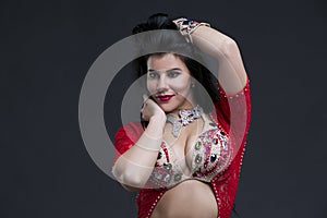 Young beautiful exotic eastern women in ethnic red dress on gray background