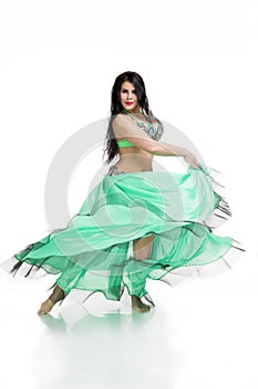 Young beautiful exotic eastern women performs belly dance in ethnic green dress. Isolated on white background