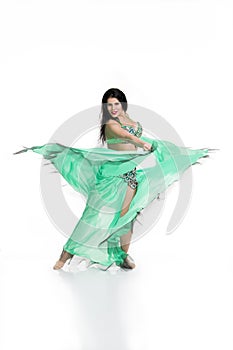 Young beautiful exotic eastern women performs belly dance in ethnic green dress. Isolated on white background