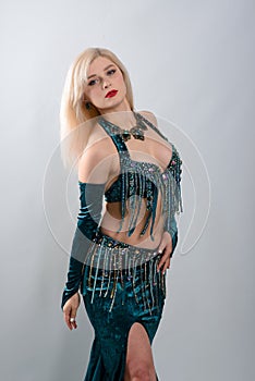 Young beautiful exotic eastern women performs belly dance in ethnic green dress.  on white background. Studio shot