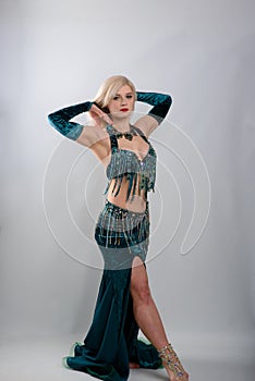 Young beautiful exotic eastern women performs belly dance in ethnic green dress.  on white background. Studio shot