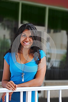 Young beautiful exotic woman smiling from balcony