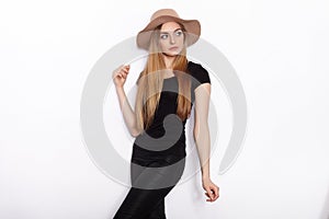 Young beautiful fashion model in women black t-shirt trendy hat black torn jeans posing in studio against white background