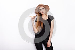 Young beautiful fashion model in women black t-shirt trendy hat black torn jeans posing in studio against white background