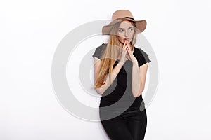 Young beautiful fashion model in women black t-shirt trendy hat black torn jeans posing in studio against white background