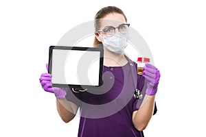 Young beautiful female doctor holding urine sample and tablet in her hands in medical mask and sterile gloves on white