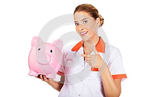 Young beautiful female doctor or nurse holding a piggybank