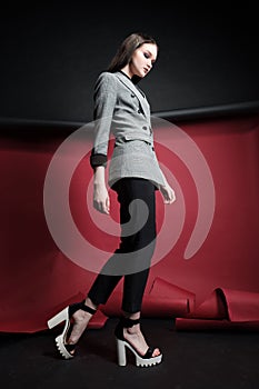 Young beautiful female fashion model in a business stylish suit on a red and black background.