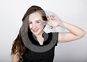 Young beautiful female Hairdresser posing with scissors