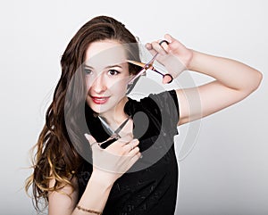 Young beautiful female Hairdresser posing with scissors