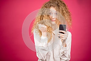 Young beautiful female with messy hair holding mobile phone