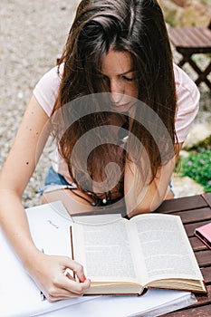 Young beautiful female sitting outside and studying hard.