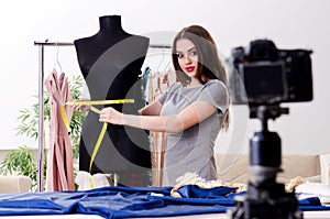 Young beautiful female tailor recording video for her blog