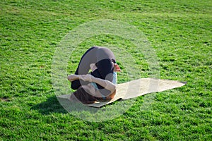Young beautiful fit woman doeing yoga asans on the green grass with yoga mat