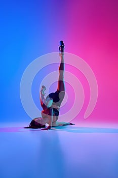 Young beautiful flexible woman dancer on high heels posing on floor in contemporary dance style, pole dance in colorful