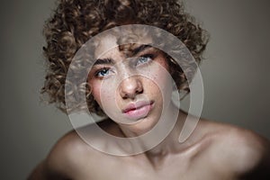 Young beautiful freckled girl with curly hair and clean makeup, selective focus