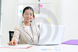 Young beautiful friendly operator woman with headset working in a call center. customer service pay attention and talking to