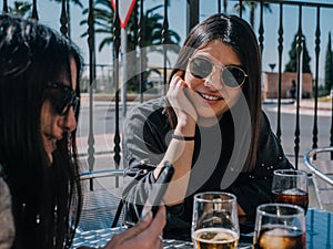 Young and beautiful friends having a refreshing drink on a terrace of a day bar