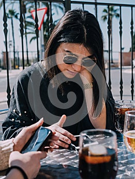 Young and beautiful friends having a refreshing drink on a terrace of a day bar