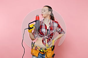 Young beautiful fun handyman woman in plaid shirt, denim shorts, kit tools belt full of variety instruments holding