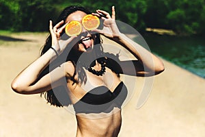 Joven hermoso ridículo verano posesión naranja en ojos sonrisa a risa sobre el Playa en soleado verano. 