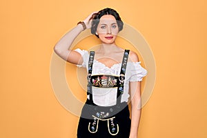 Young beautiful german woman with blue eyes wearing traditional octoberfest dress confuse and wonder about question