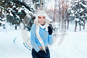 Young beautiful girl with afro hair wearing hat, blue sweater posing in winter park. Christmas, winter holidays concept.