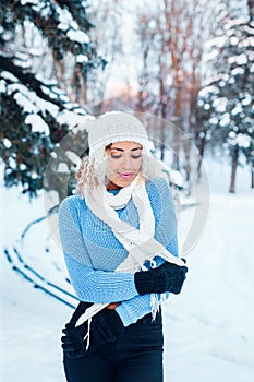 Young beautiful girl with afro hair wearing hat, blue sweater posing in winter park. Christmas, winter holidays concept.